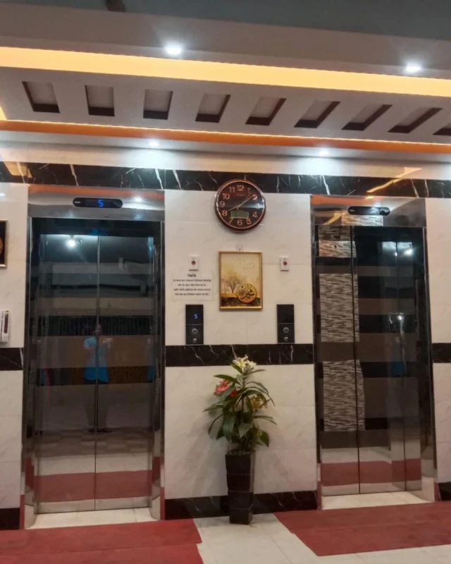 Elevator lobby with warm brass cove lighting, marble tiling and a decorative clock