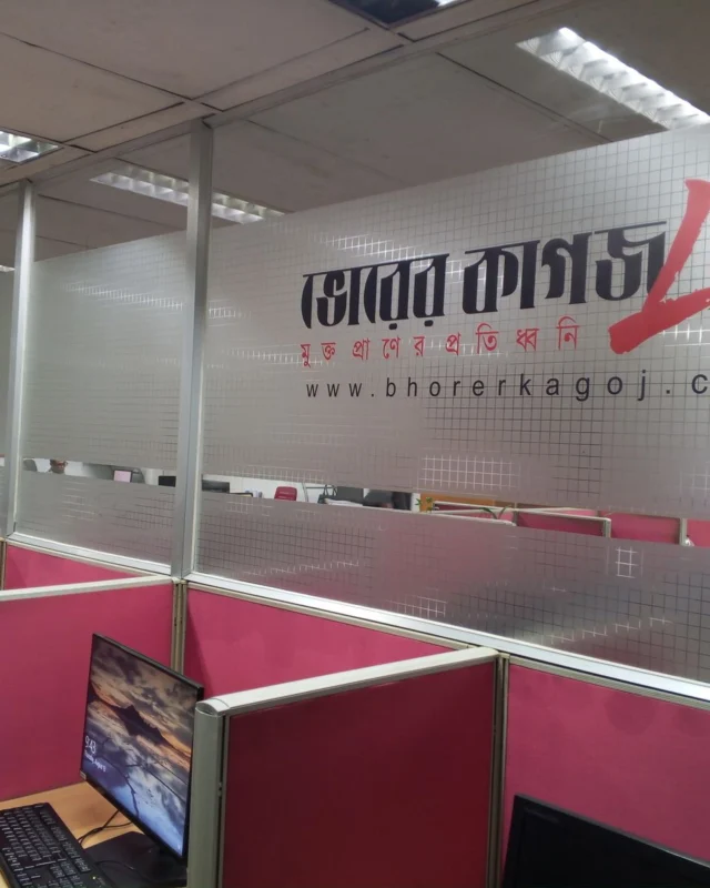 Open newsroom with pink modular workstation partitions and etched glass branding