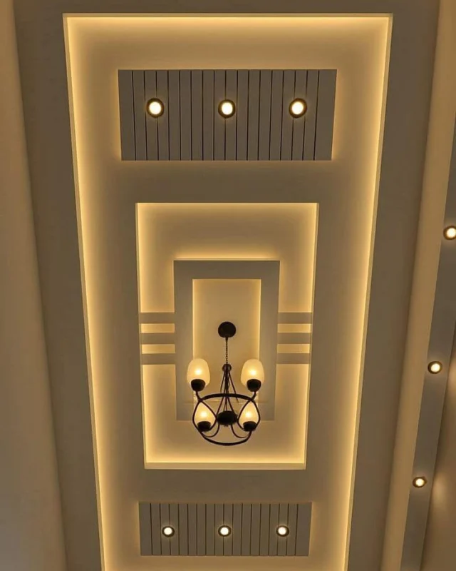 Multi-tier false ceiling with cove lighting and a statement chandelier